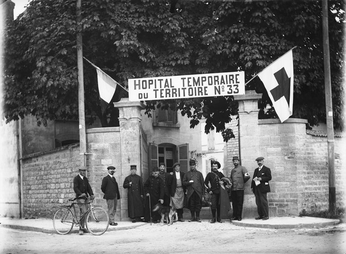 “Hôpital temporaire du territoire n°33” : devant un portail grilles ouvertes, soldats, soignants, drapeau de la Croix-Rouge (titre usuel), Jules Misserey, 20e siècle