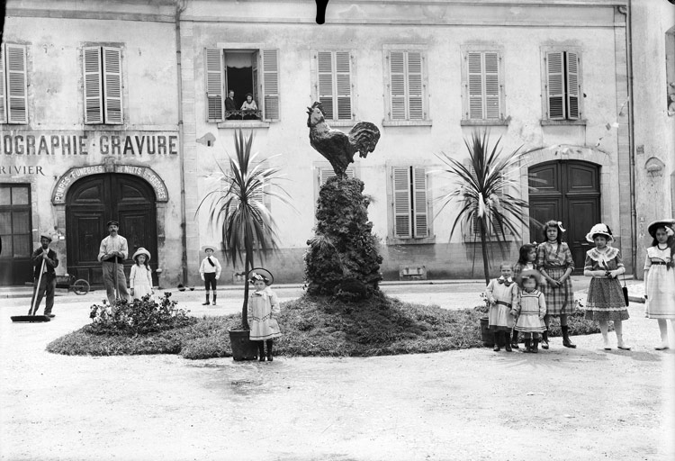 Homme au travail et enfants devant les pompes funèbres. Sur la place, coq sur un piédestal et palmiers en pot : Place Monge (titre usuel), Jules Misserey, 20e siècle, 1ère moitié 20e siècle, 2e quart 20e siècle