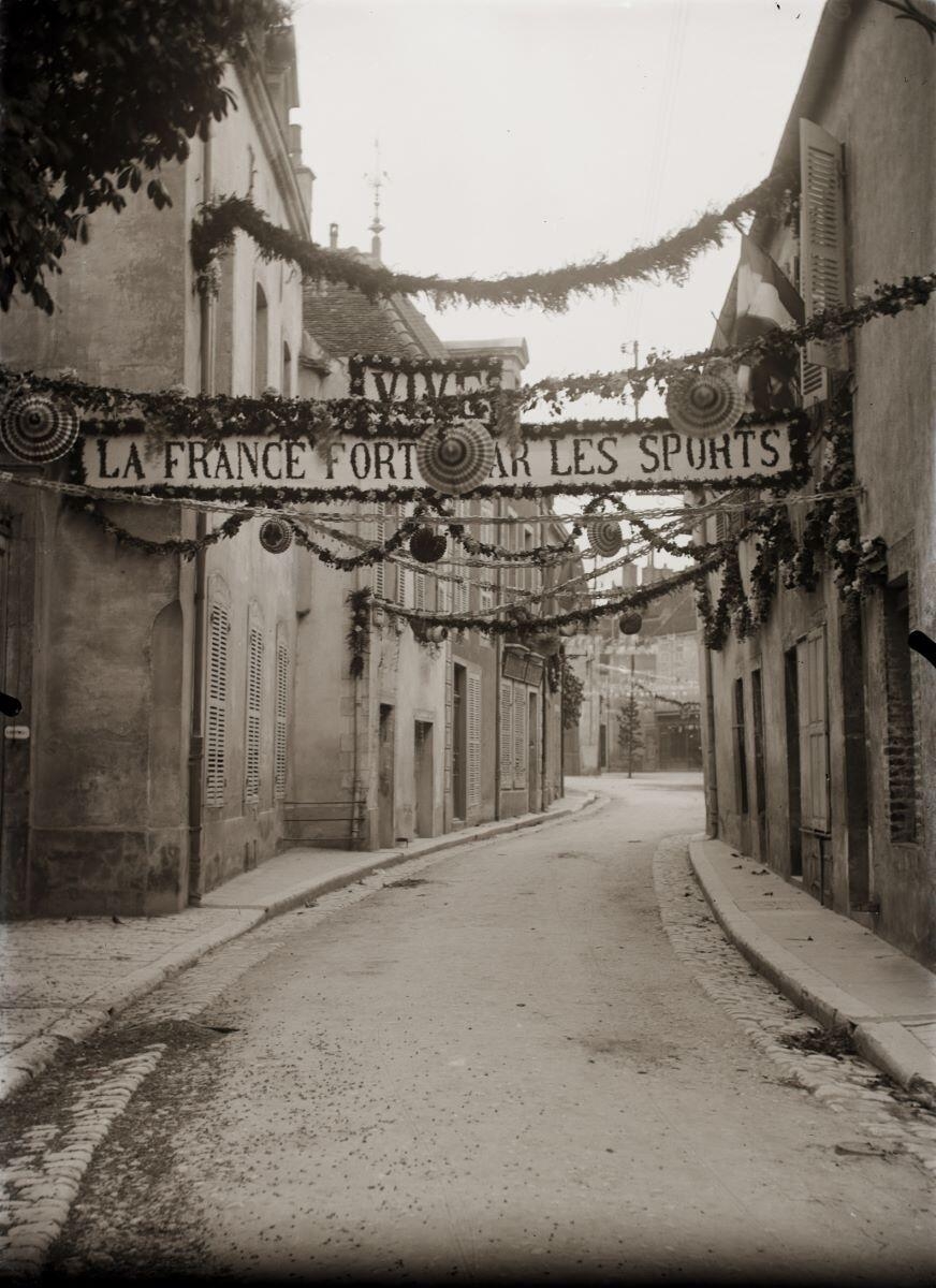 Nuits-Saint-Georges - Fête du sport ? La France forte par les sports - Vue sur rue décorée avec guirlandes de feuillages (titreusuel), Jules Misserey, 1ère moitié 20e siècle