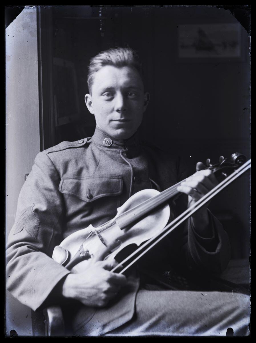 Soldat américain en uniforme posant assis, son violon entre les mains_0