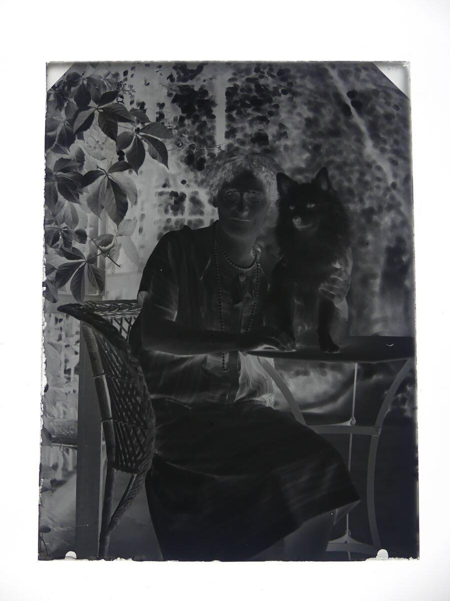 Portrait d'une femme et de son chien posant dans un fauteuil d'osier au jardin, Louis Hertig, 1ère moitié 20e siècle