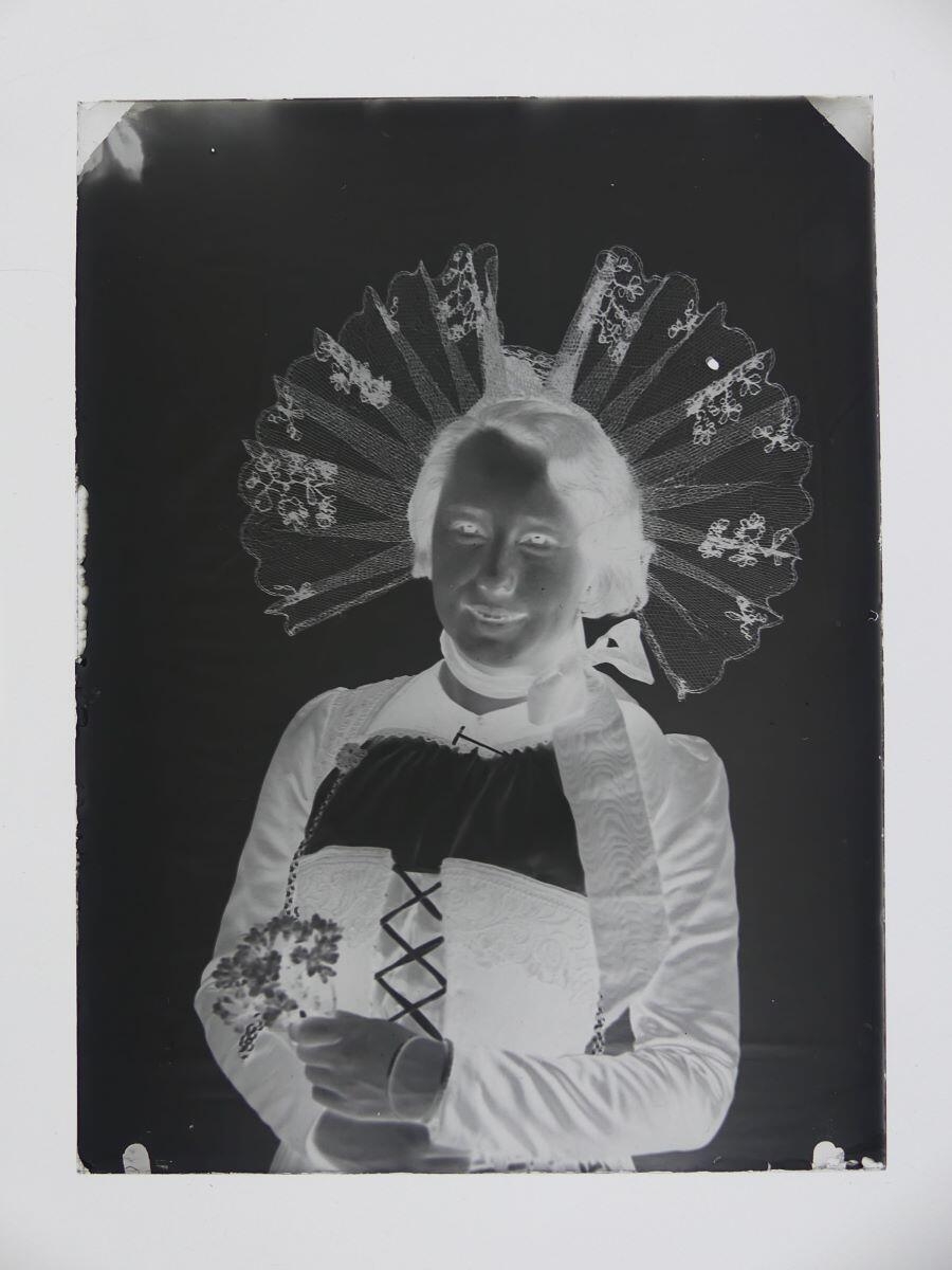 Jeune femme en costume traditionnel suisse, vue en buste, tenant un bouquet de fleurs, Louis Hertig, 1ère moitié 20e siècle