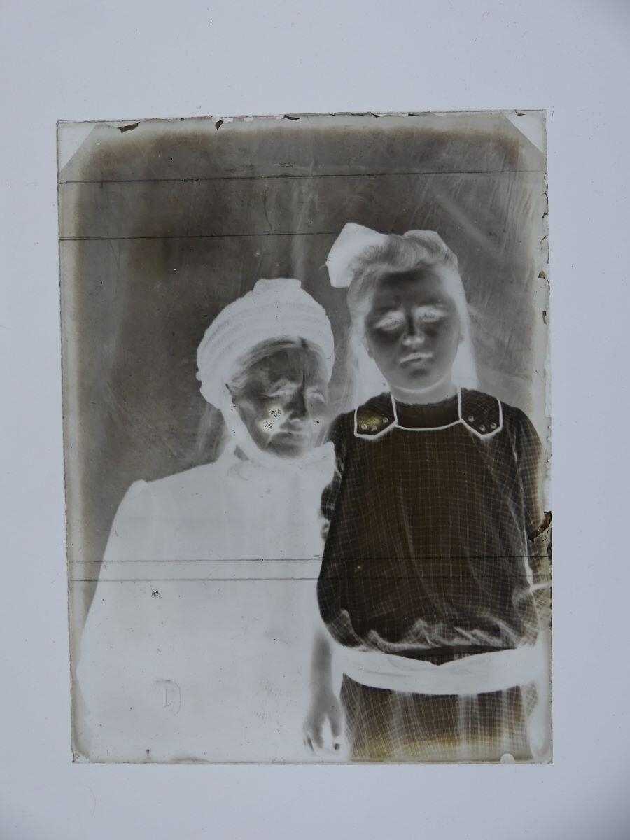 Petite fille et femme âgée posant côte-à-côte dans l'atelier, Louis Hertig, 1ère moitié 20e siècle