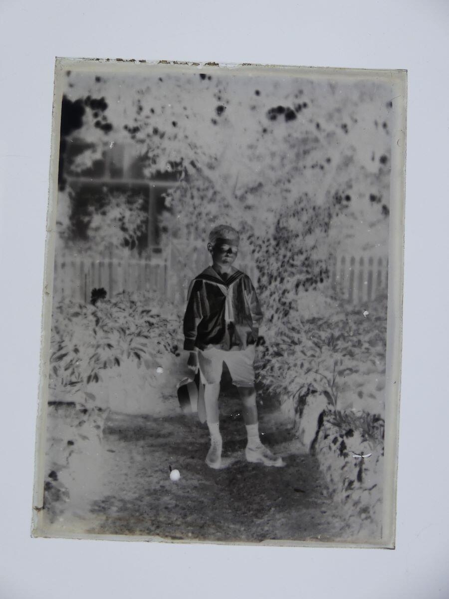 James Hertig enfant, en costume marin, tenant son chapeau à la main, posant dans un jardin, Louis Hertig, 1ère moitié 20e siècle
