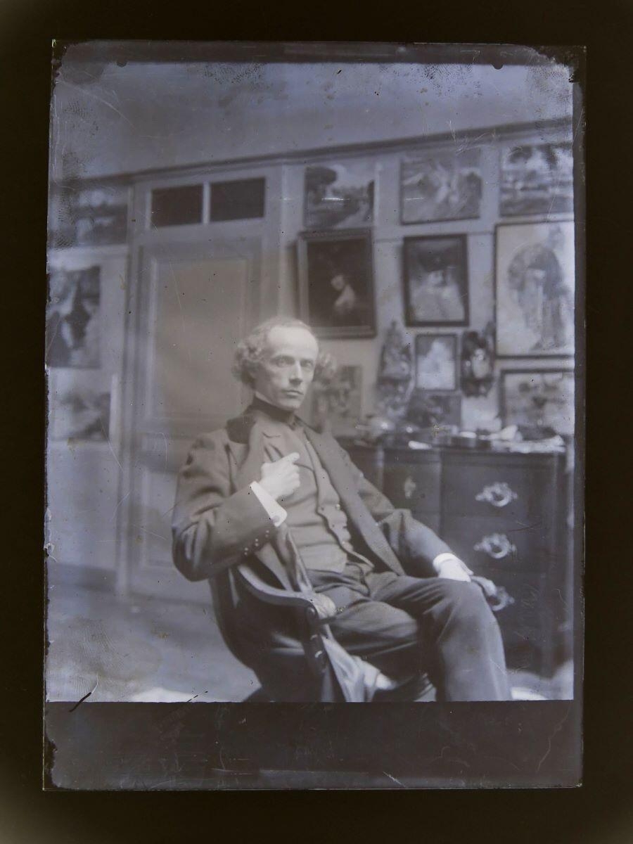 Portrait d'homme posant dans un fauteuil dans l'atelier du peintre Léon Tirode, Studio Meusy, 4e quart 19e siècle, 1ère moitié 20e siècle