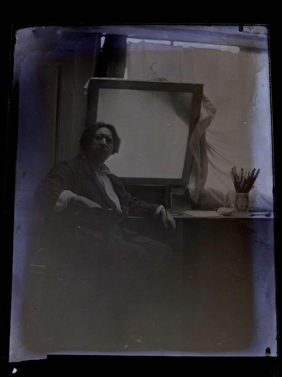 Portrait du peintre Léon Tirode dans son atelier assis devant une table de travail, assis sur la gauche, Studio Meusy, 4e quart 19e siècle, 1ère moitié 20e siècle