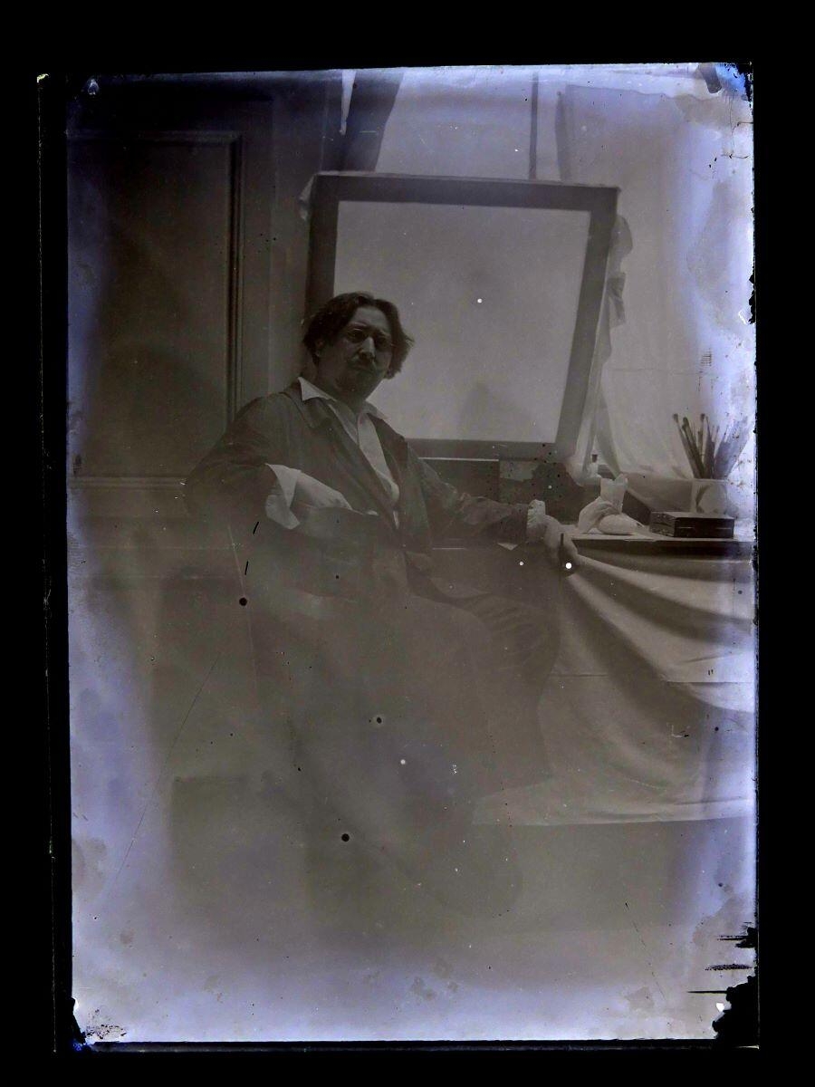 Portrait du peintre Léon Tirode dans son atelier assis devant une table de travail, assis sur la gauche, Studio Meusy, 4e quart 19e siècle, 1ère moitié 20e siècle