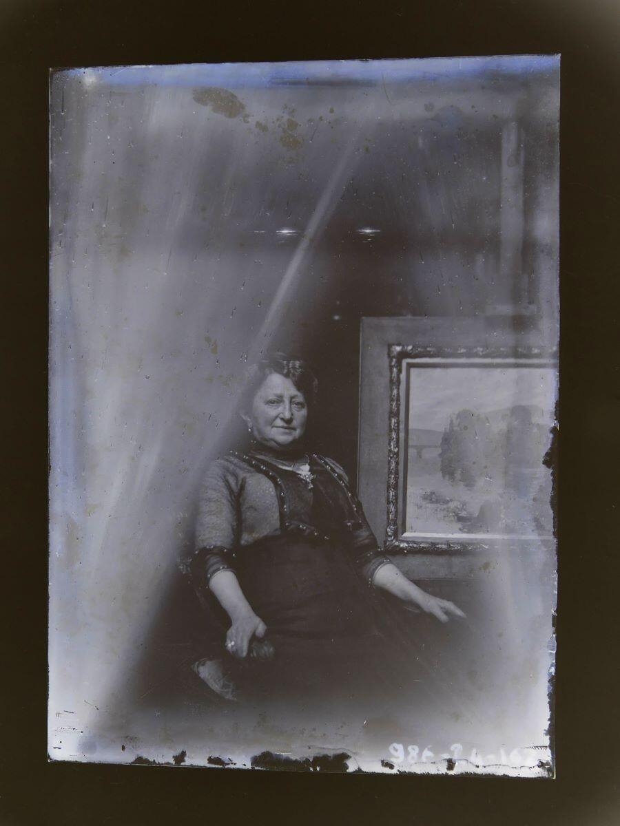 Portrait d'une femme assise dans l'atelier, posant à côté d'un tableau, Léon Tirode, 4e quart 19e siècle, 1ère moitié 20e siècle