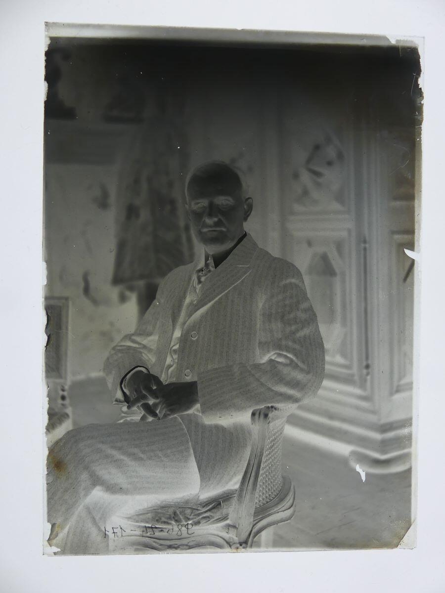 Portrait d'homme en costume rayé, jambes croisées, posant dans l'atelier_1