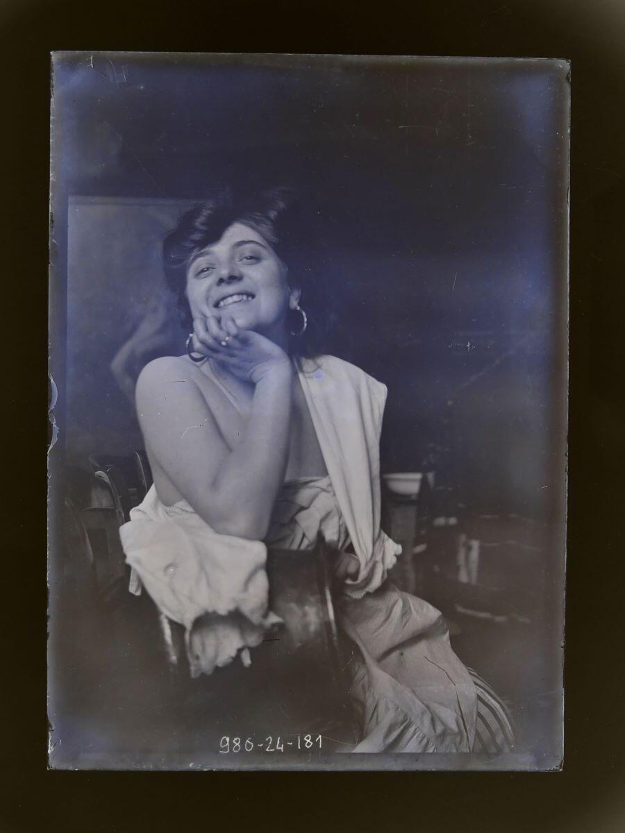 Modèle souriant, épaule nue, le menton dans la main droite, posant dans l'atelier_0
