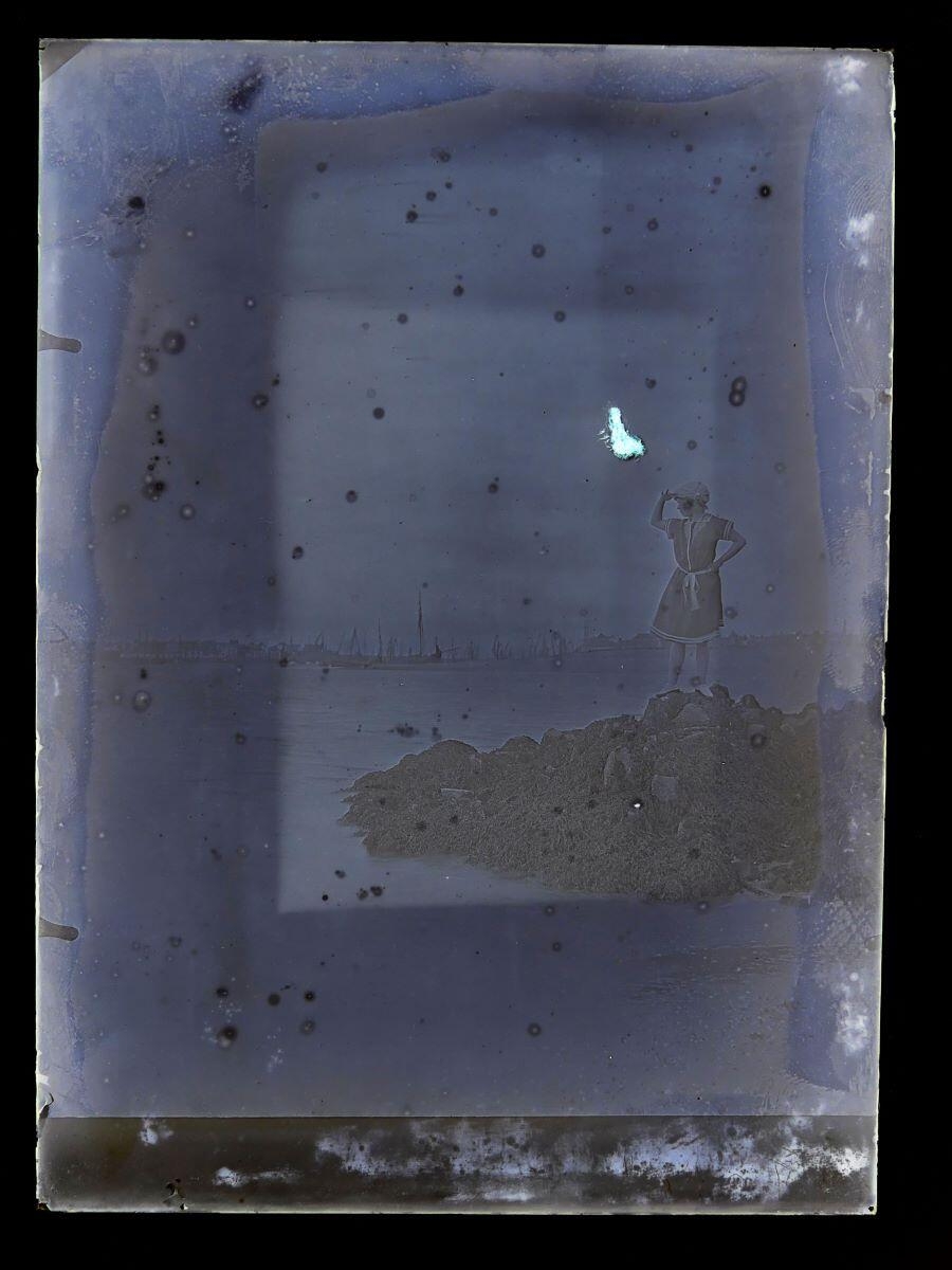 Femme en costume de bain, sur des rochers, regardant au loin la mer et un port, Léon Tirode, 4e quart 19e siècle, 1ère moitié 20e siècle