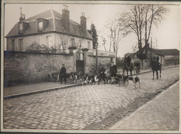 Photographie d'un album en maroquin vert comprenant 24 photographies : Equipage Par Monts et Vallons, piqueux à cheval, valet de chiens et meute sur la chaussée, Georges Royer, 1920 avant