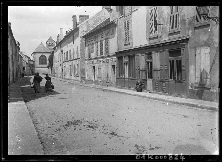 Rue du village, enseigne de « Genestre Tonnelier », chevet de l’église en fond de perspective