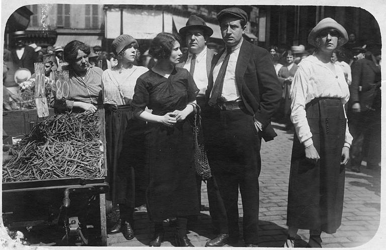 Personnages au milieu d'une rue pavée près d'une charrette de maraîcher avec des haricots 'sans fil'