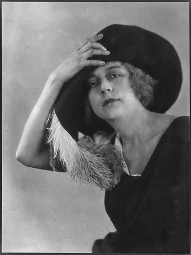 Portrait de Nathalie Kovanko tenant son chapeau garni d'une plume