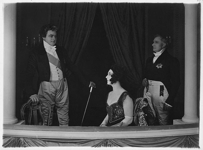 Nathalie Lissenko assise et deux hommes dans un balcon de théâtre