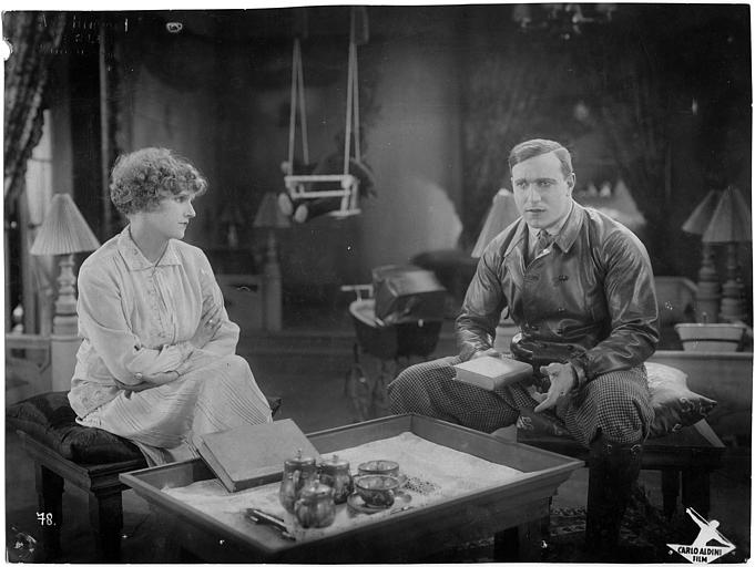 Carlo Aldini tenant un livre, et une femme, assis devant une table basse