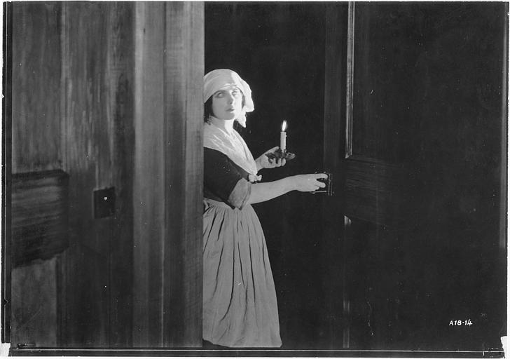 Géraldine Farrar, dans le rôle de Marcia Manot, porte un bougeoir et ouvre une porte