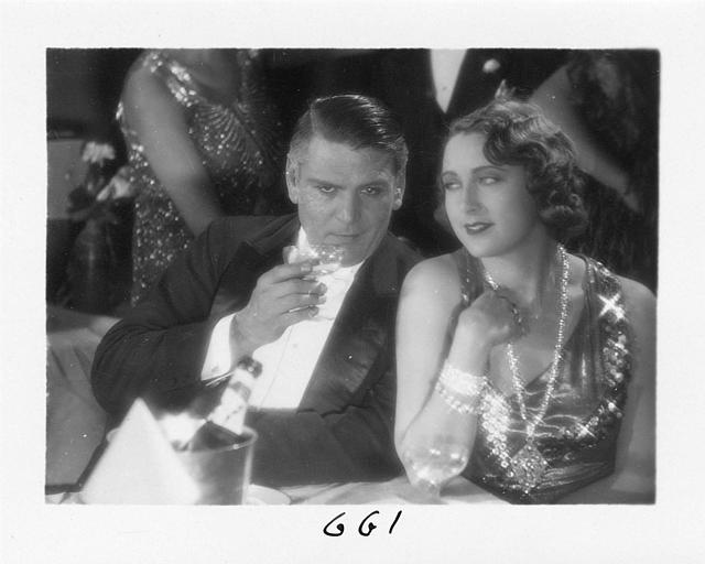 Un homme et Diana Karenne dans le rôle de Mme Beauchêne buvant du champagne durant une soirée dans 'Fécondité' de Nicolas Evreinoff et Henri Étiévant