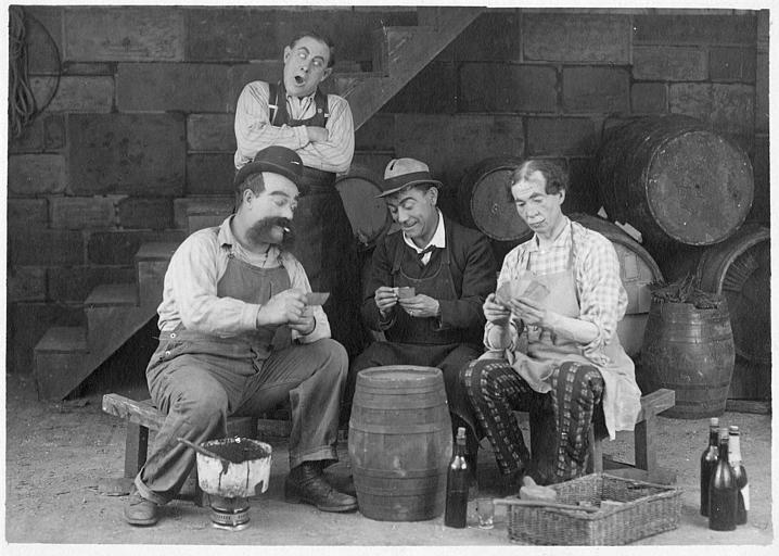 Dans une cave, Rémond Frau qui interprète Dandy joue aux cartes sur un tonneau avec Max, Louis et Ulysse dans un épisode de 'Dandy' de Georges Rémond