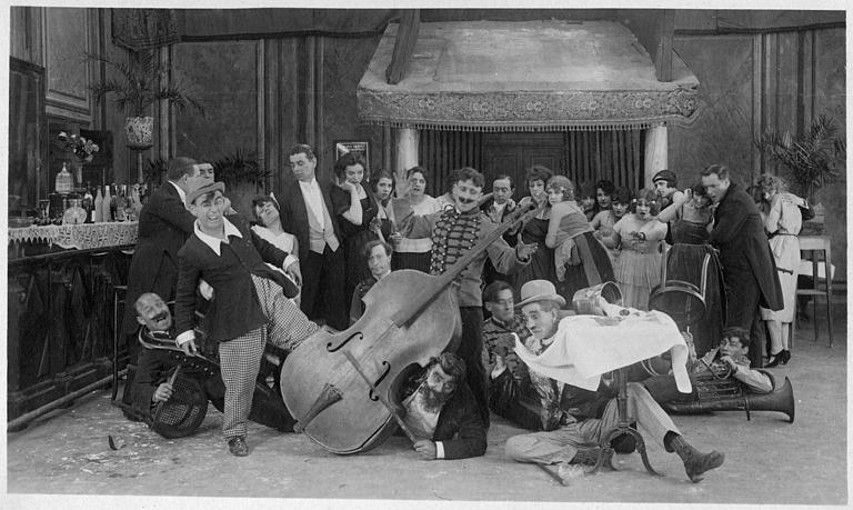 Dans une salle de bal, les musiciens de l'orchestre ont glissé de leur balcon au milieu des danseurs : Rémond Frau dans le rôle de Dandy, Max, Foche et Smote dans un épisode de 'Dandy' de Georges Rémond