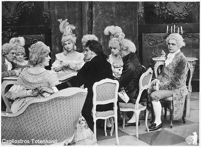 Personnages en costumes dont Martha Novelly jouant aux cartes autour d'une table