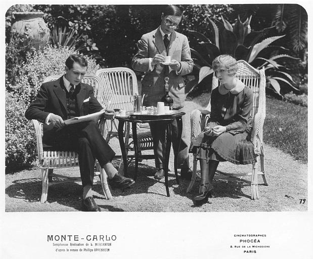 Dans un jardin, Betty Balfour et Charles Lamy sont assis autour d'une table et boivent le café en présence d'un troisième homme debout derrière eux