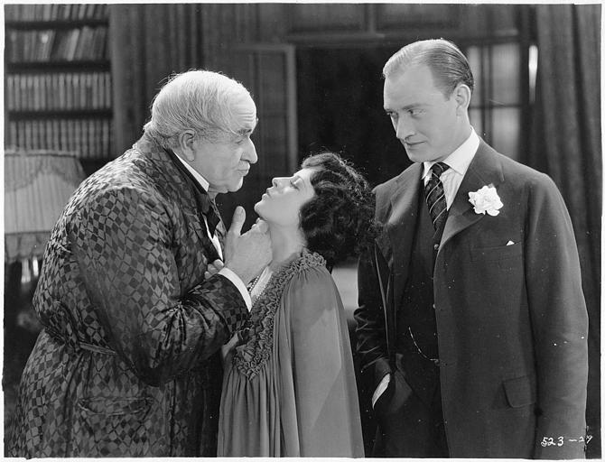 May McAvoy dans le rôle de Virginia Bullivant mimant un baiser à un homme plus âgé, en présence d'un autre homme dans 'Grumpy' de  William C. DeMille