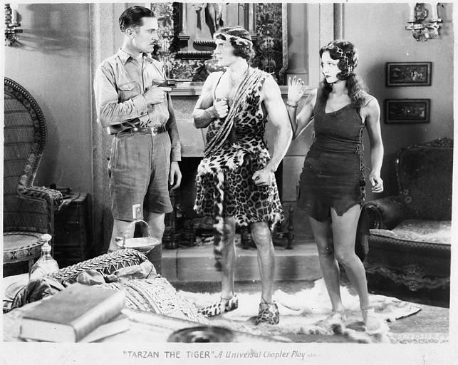 Un homme pointant un revolver sur Tarzan interprété par Franck Merril en présence de Natalie Kingston dans le rôle de Mary Trevor