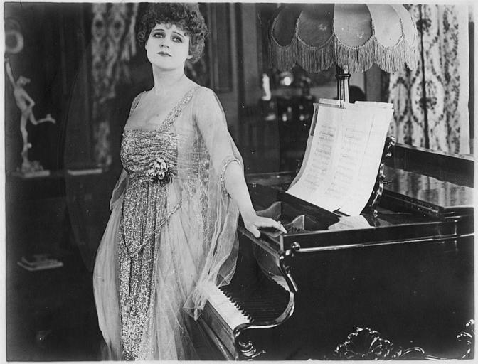 Lillian Walker dans le rôle d'Elizabeth Holt appuyée sur un piano