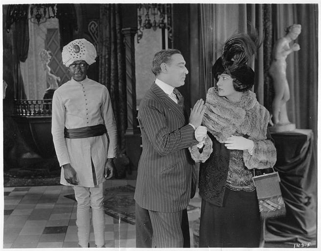 Un homme pousse Rosemary Theby (interprétant  Mrs. Beatrice Mason) par l'épaule en présence d'un personnage costumé en hindou : Rosemary Theby