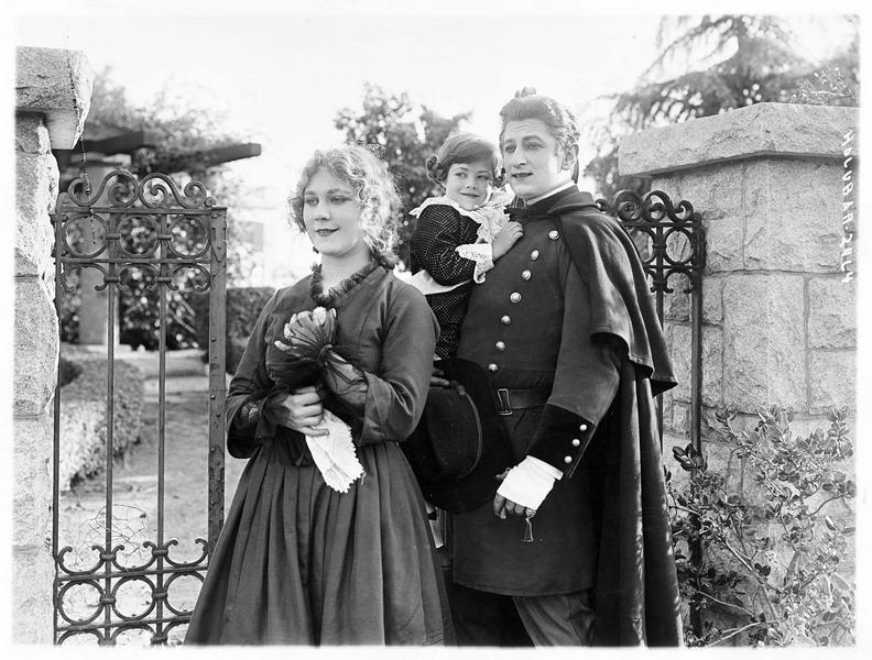 Helen Reed (L. Lovely) et Jerry Brennon (A. Holubar) tenant un enfant dans ses bras