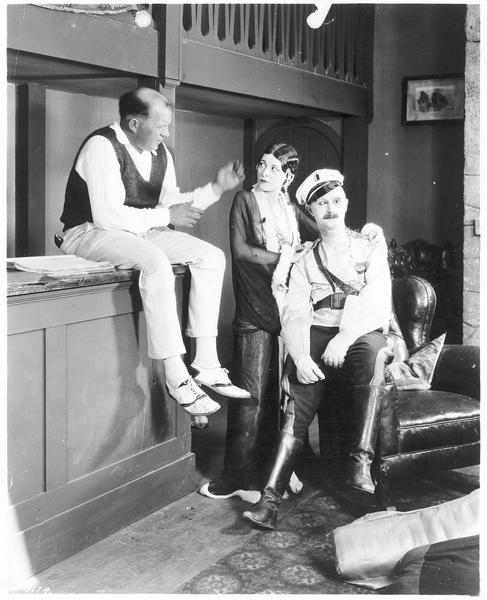 Un homme assis sur le comptoir parlant à une femme dont les mains reposent sur les épaules d'un cavalier (B. Turpin)