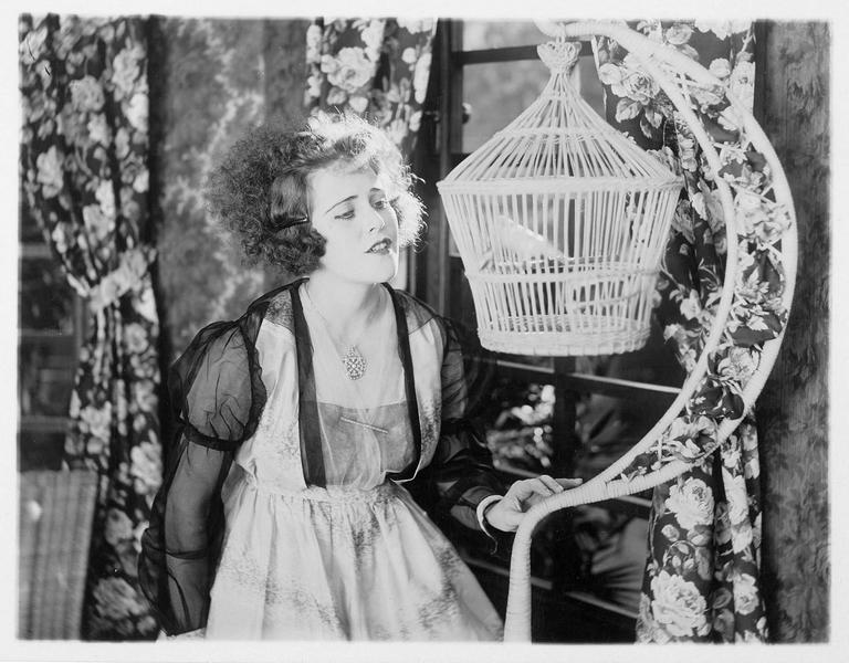 Portrait de Ruth Roland devant une cage à oiseau