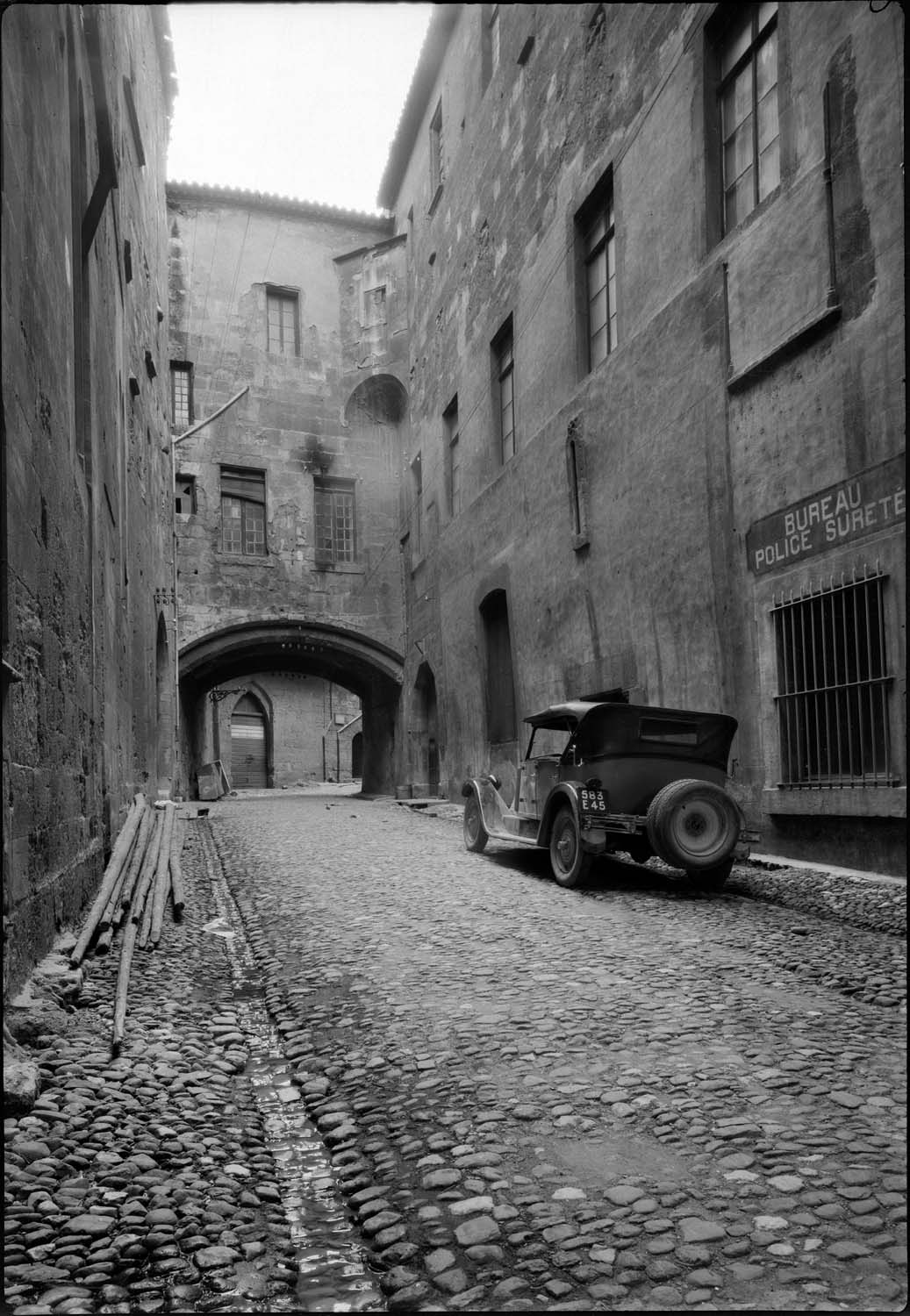 Perspective depuis une rue ; sur la droite, enseigne « Bureau police Surete »