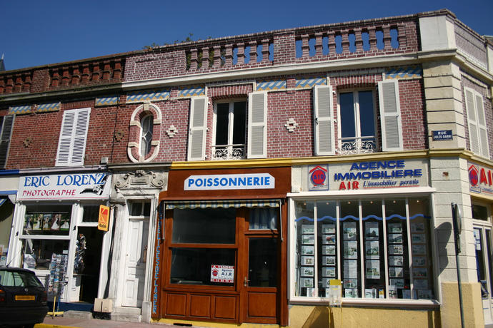 devantures de boutiques ; enseignes professionnelles ; RDC enduit ; 1er étage brique ; frise de carreaux de céramique ; balustrade.