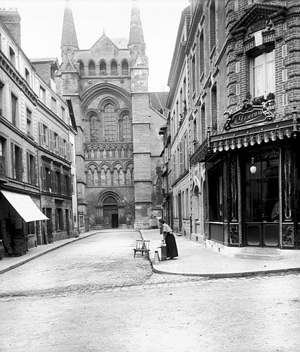 Portail sud vu depuis la rue, femme tirant de l'eau d'une pompe