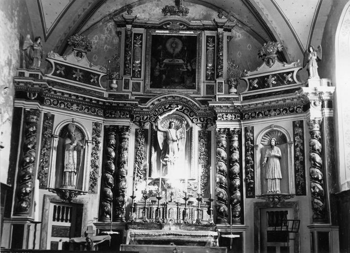 Retable, tableau, statues (3) : Anges adorant le Saint-Sacrement (fronton), Saint Blaise (à gauche), Saint Michel (au centre), un saint personnage (à droite), retable architecturé à trois travées et deux niveaux, richement ornementé, bois sculpté, peint, doré, huile sur toile