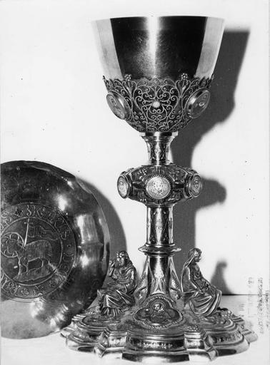 Calice, patène : décor de statuettes représentant la Vierge et saint Joseph, assis sur le pied, cabochons au émaux représentant saints personnages et chérubins, décor d'arabesques en filigranes, patène ornée de l'Agneau pascal, argent doré, émaux - © Ministère de la Culture (France), Médiathèque du patrimoine et de la photographie (objets mobiliers), tous droits réservés