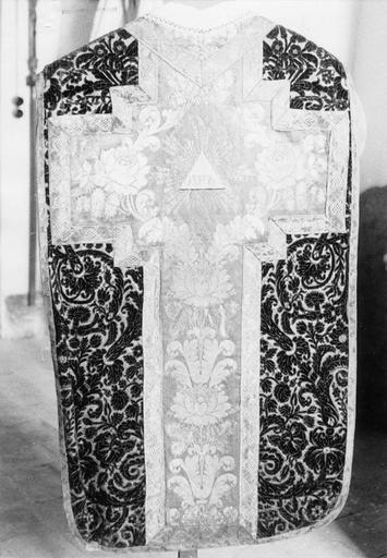 Chasuble en velours façonné grenat à motifs de rinceaux fleuris, agrémenté d'une croix en soie damassée à décor de fleurs, délimitée par un galon de fils d'or