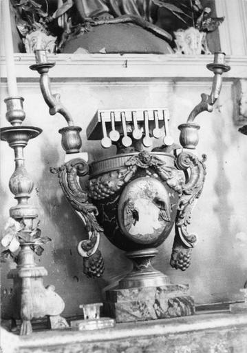 Tabernacle en forme de vase, au motif central lacunaire, orné d'un chérubin, de grappes de raisin, aux anses en forme de volutes rocaille surmontées chacune d'un bras de lumière, bois sculpté, peint, doré - © Ministère de la Culture (France), Médiathèque du patrimoine et de la photographie (objets mobiliers), tous droits réservés