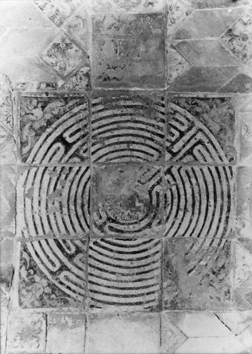 Carrelage de sol : représentation du  labyrinthe de la chapelle de l'évêque et du motif décoratif constitué de carreaux en losange avec des motifs floraux, l'encadrement se compose d'une frise de carrés ornés de rinceaux végétaux, 1535, détail du labyrinthe formé de neuf carreaux, dans le cercle central se trouve un personnage portant une lampe où flotte une flamme portant le mot MINOT (effacé)