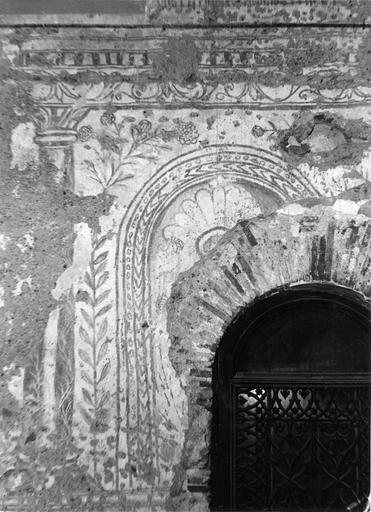 Peinture monumentale : fragment représentant un arc ou une niche, surmonté par une corniche ornée de rinceaux végétaux supportée par une colonne, ensemble décoré de fleurs, peinture sur enduit