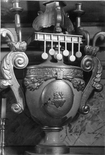 Tabernacle en forme de vase avec, au centre de la porte, un motif représentant deux coeurs enlacés, aux anses surmontées de deux bras de lumière chacune, et au col fermé par un Livre aux 7 Sceaux, bois sculpté, peint, doré - © Ministère de la Culture (France), Médiathèque du patrimoine et de la photographie (objets mobiliers), tous droits réservés