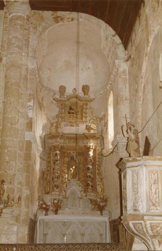 Retable architecturé à deux niveaux, le premier abritant dans une niche sculptée de faux rideaux tirés, une Vierge à l'Enfant, le second présentant la Nativité de la Vierge sculptée en bas-relief, bois sculpté, peint, doré