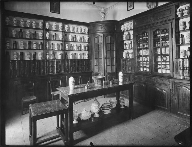 Meuble de pharmacie composé d'étagères, tiroirs et vitrine, et vue de l'ensemble de pots à pharmacie et bouteilles de l'hospice, bois taillé, faïence, verre soufflé