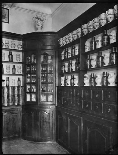 Meuble de pharmacie, détail d'une vitrine d'angle, étagères et tiroirs, bois taillé