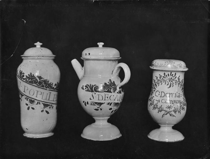 Pot à pharmacie, chevrette et pot-canon aux décors de motifs végétaux et inscriptions bleus sur fond blanc, faïence