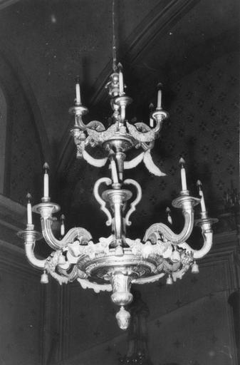 Lustre à  deux niveaux de branches en forme de volutes, reliées entre elles par des guirlandes de fleurs, et sous lesquelles on distingue des glands de passementerie, bois sculpté, doré