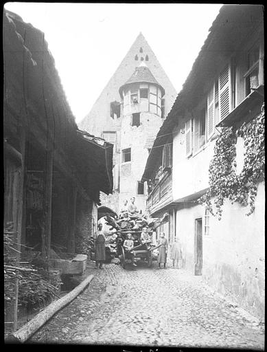 Dans une ruelle, passants en calèche, tourelle